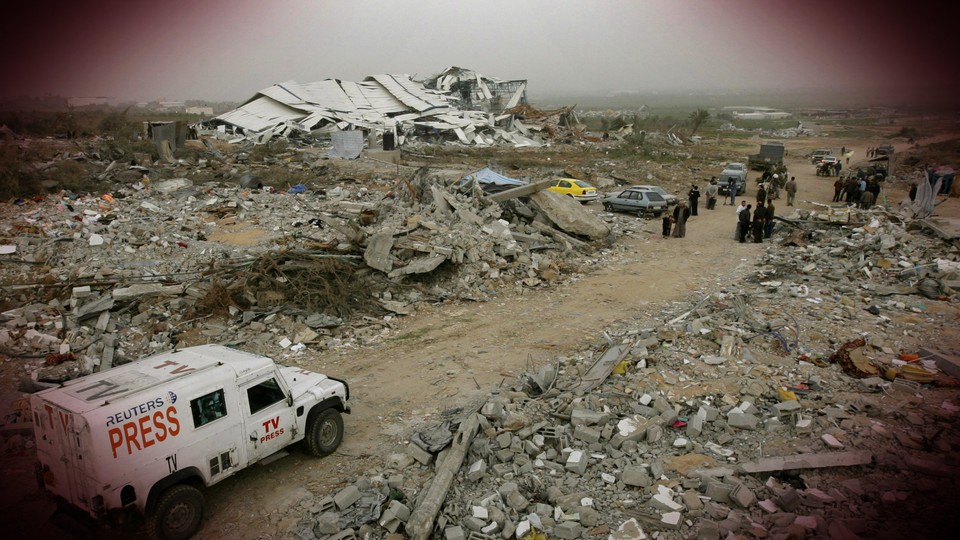 A Reuters truck drives through a bombed refugee camp in Gaza.