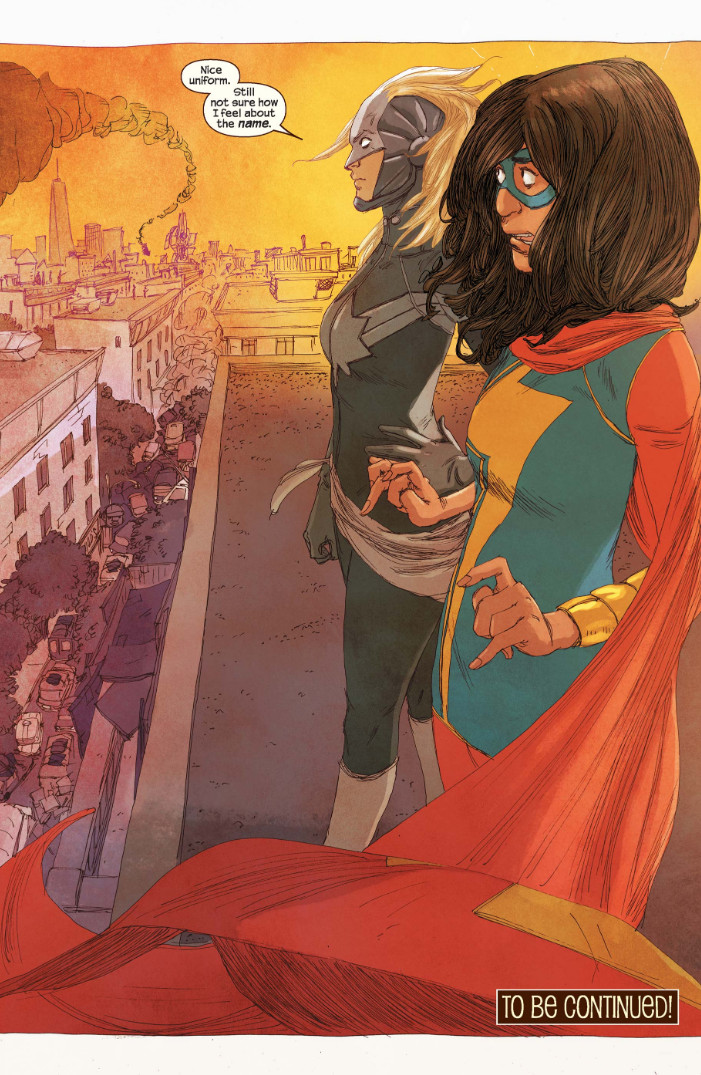 Kamala Khan and Carol Danvers stand on a rooftop. Kamala is shocked that Carol is there, as Carol says “Nice uniform. Still not sure how I feel about the name.”