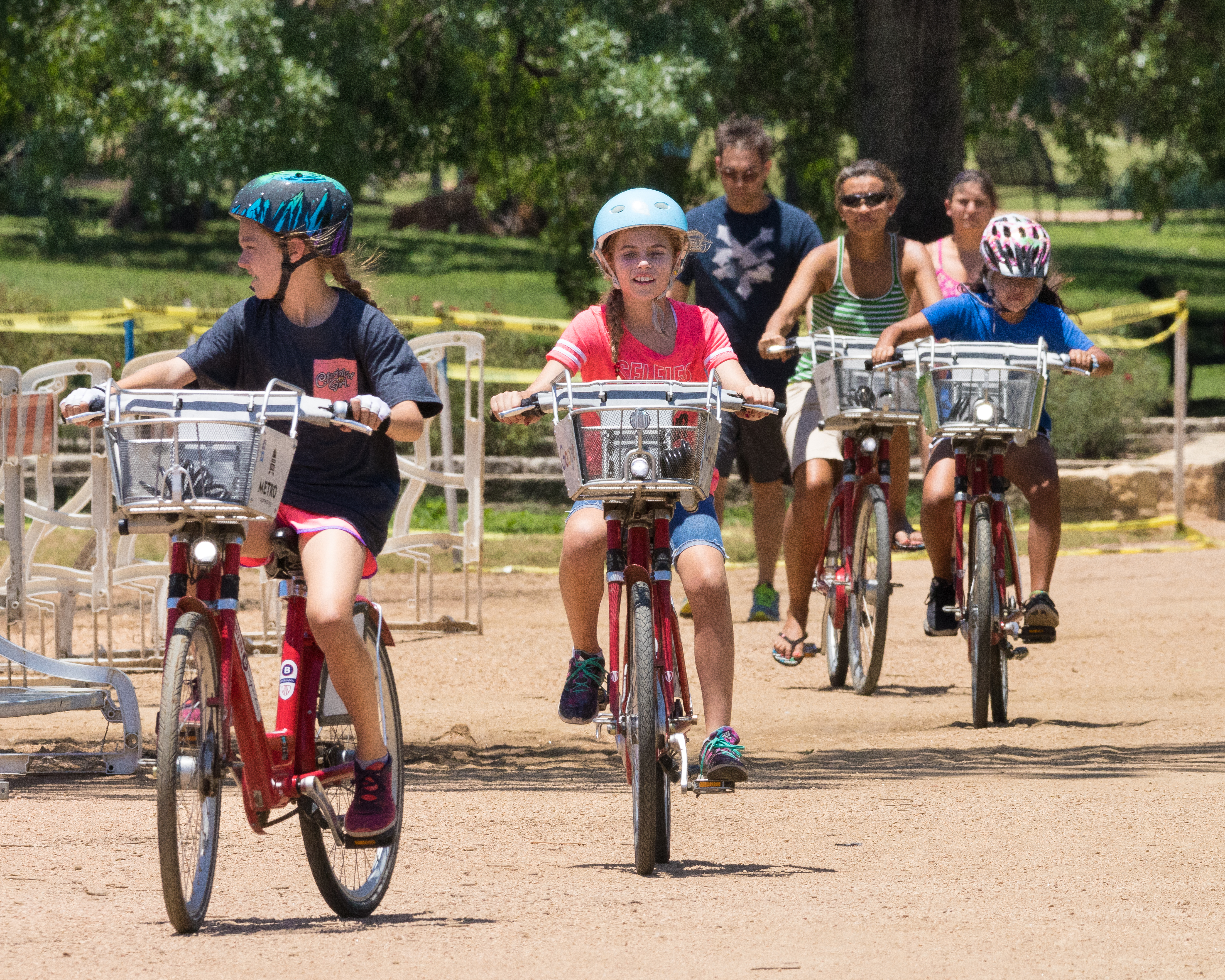 Kids and adults on similar bikes with baskets on a crushed granite trail. The bikes are part of Austin’s B-cycle rental program.
