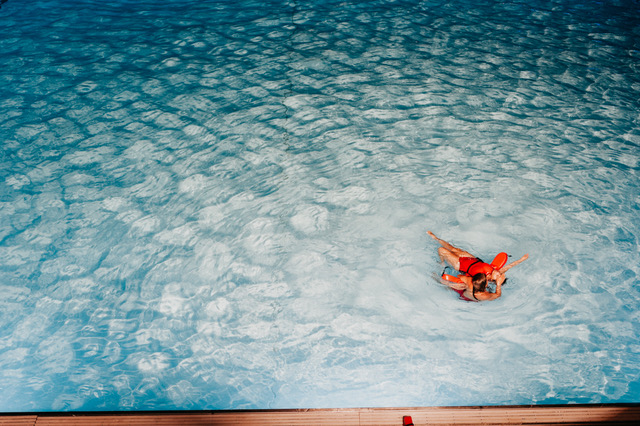 person holding another person floating in a shallow pool with lifeguard floats