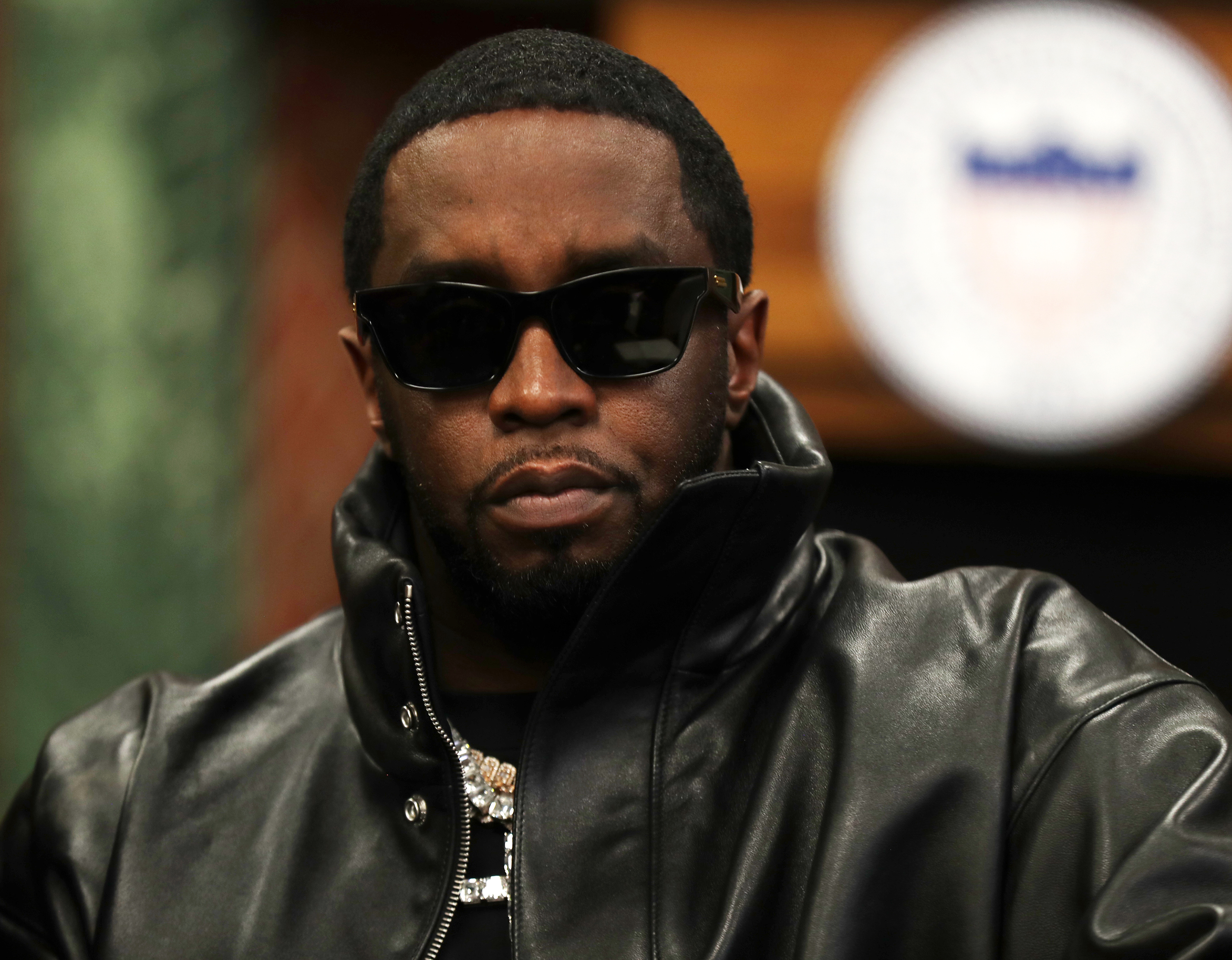 Diddy wearing sunglasses and a high-collar leather jacket.