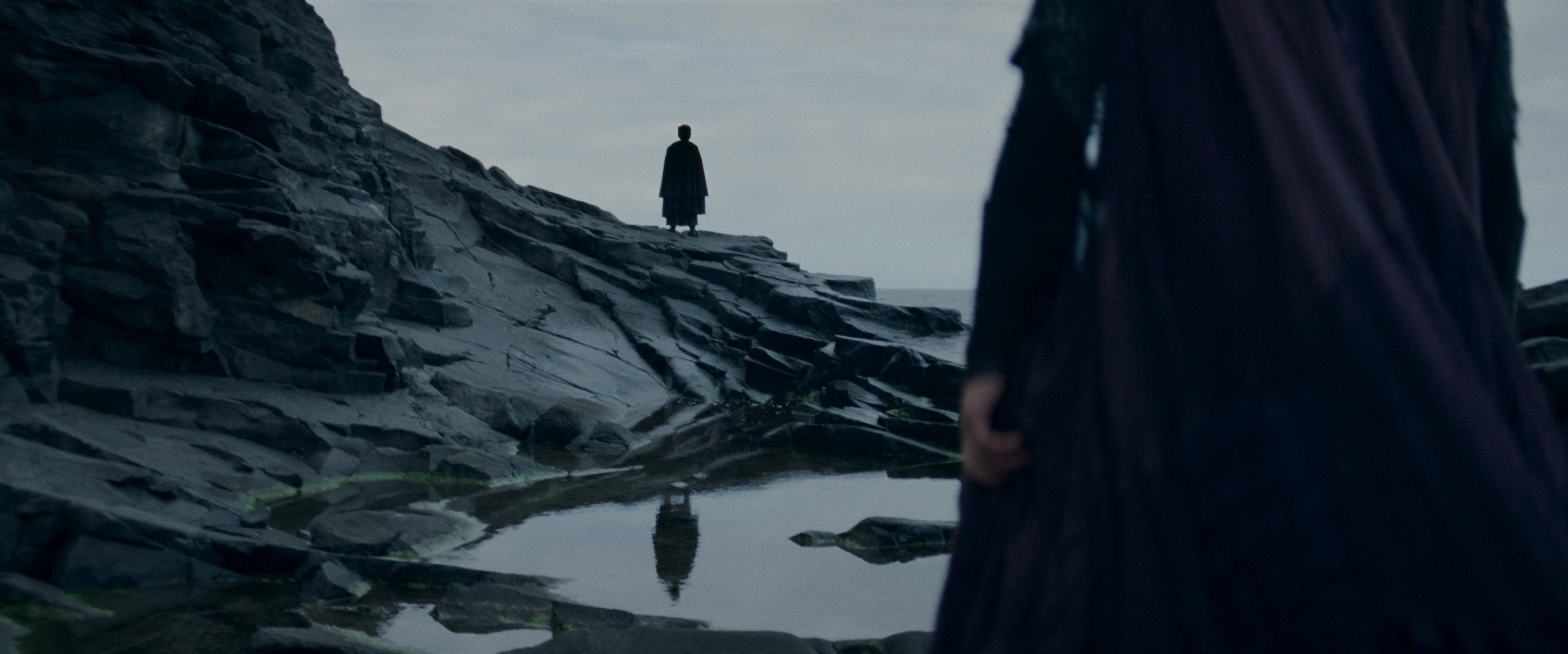 A shadowy Sith figure stands on rocks in a still from The Acolyte