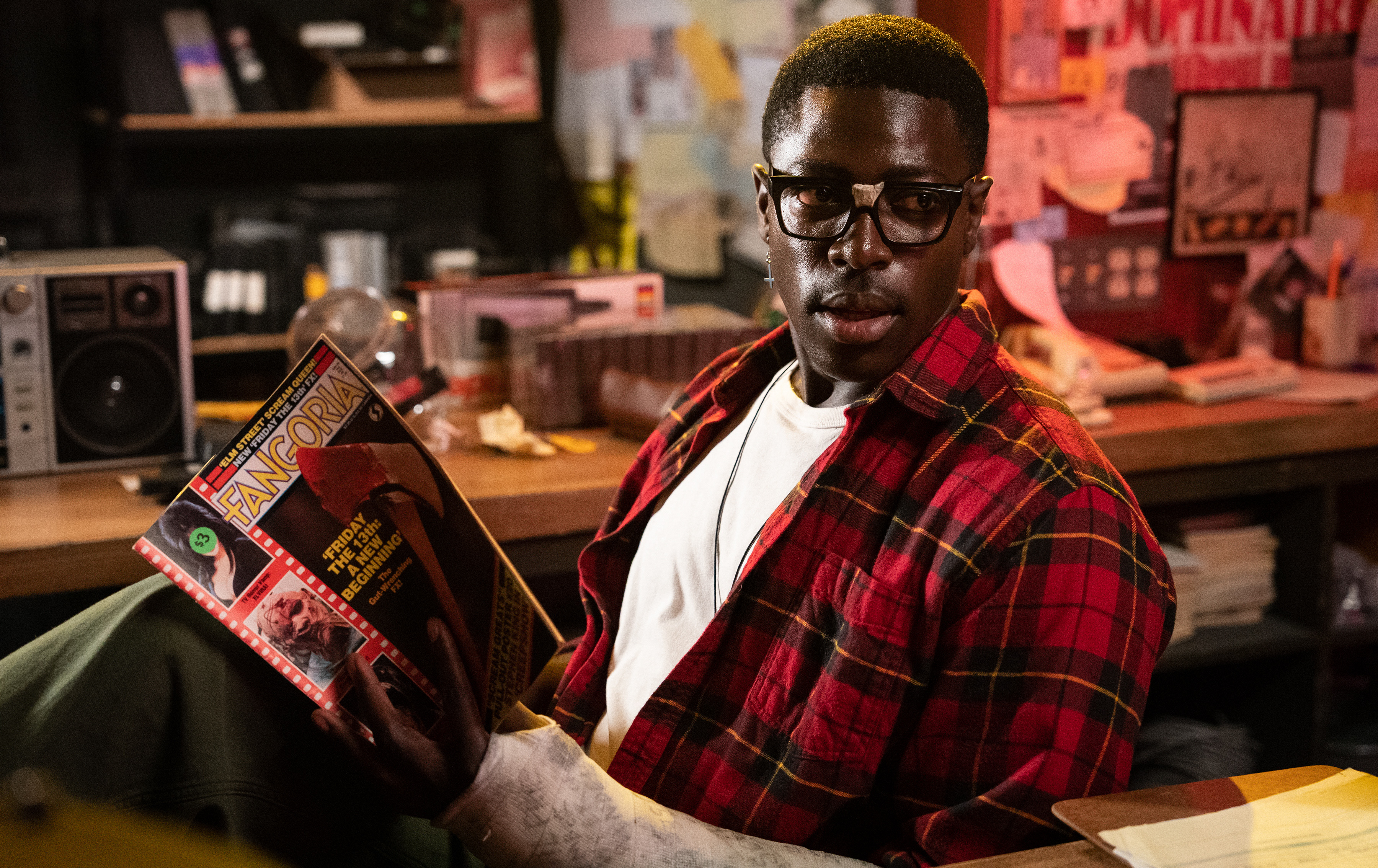 Leon (Moses Sumney) sits behind the counter of his video rental shop, reading Fangora, in Ti West’s Maxxxine