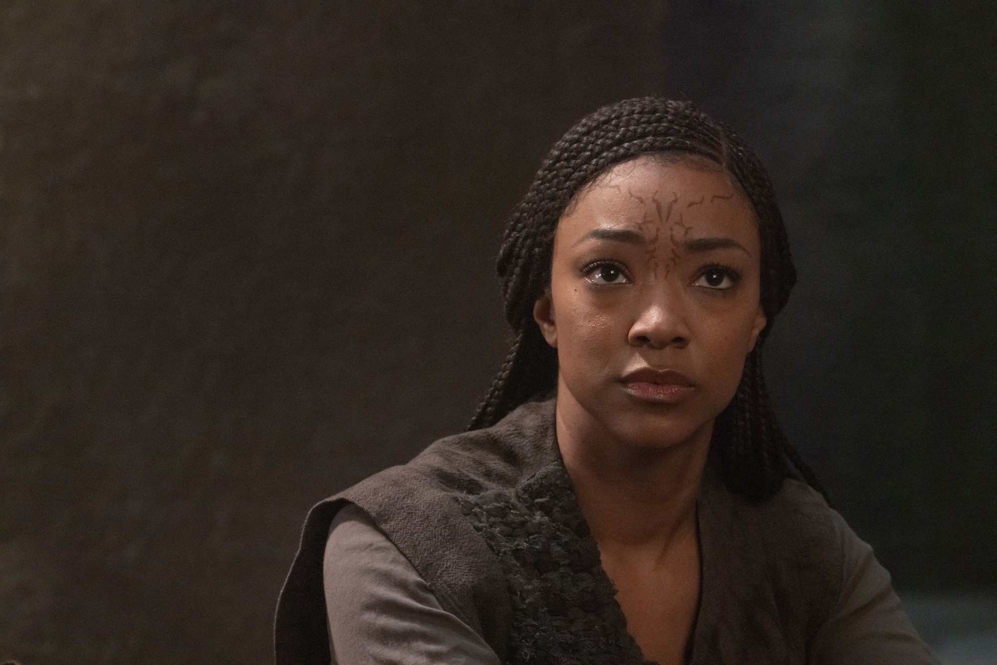 Sonequa Martin-Green as Michael Burnham in Star Trek: Discovery. She looks pensively into the distance, dressed in alien garb, with an alien marking on her forehead. 