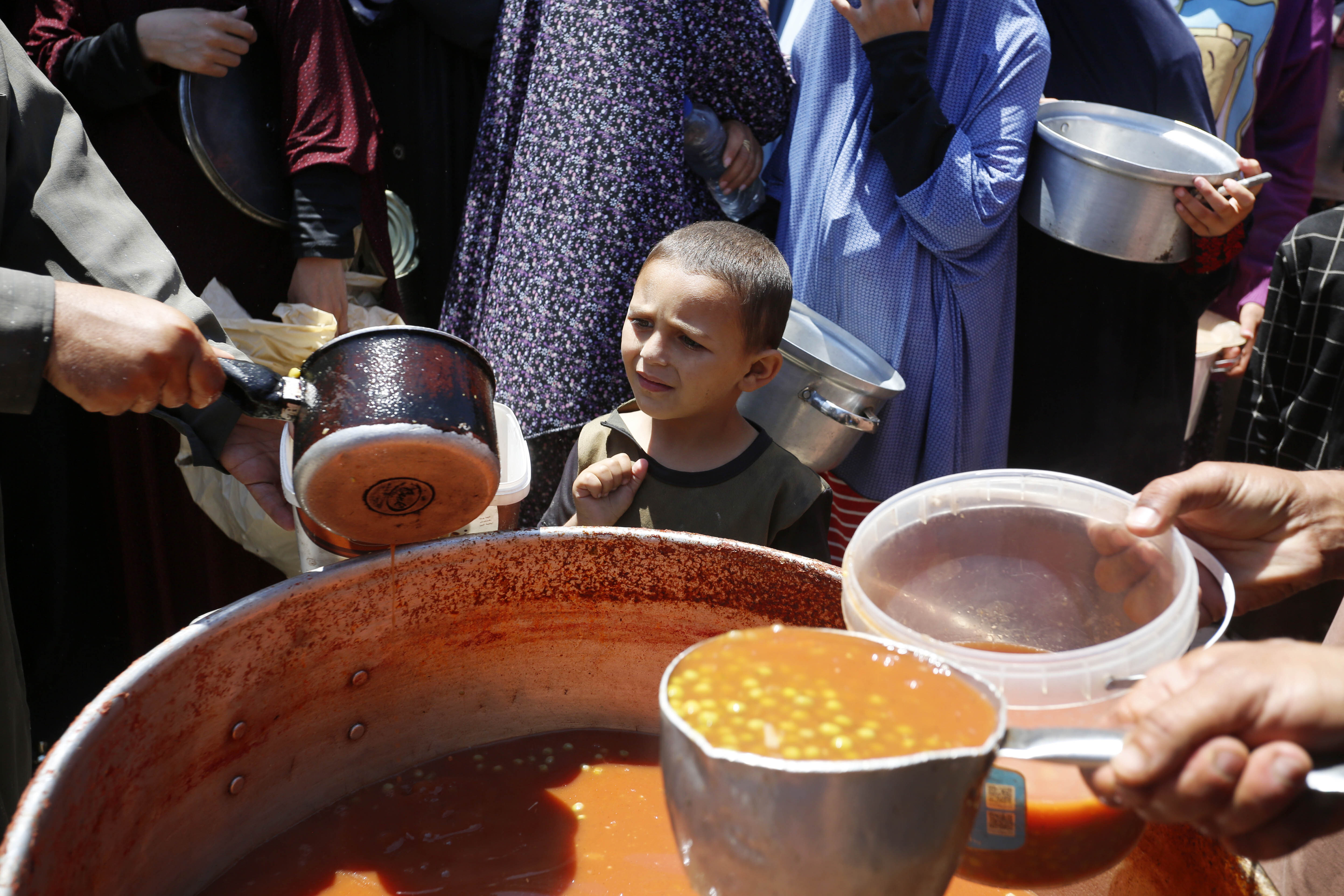 A child waits to receive a bowl of food.