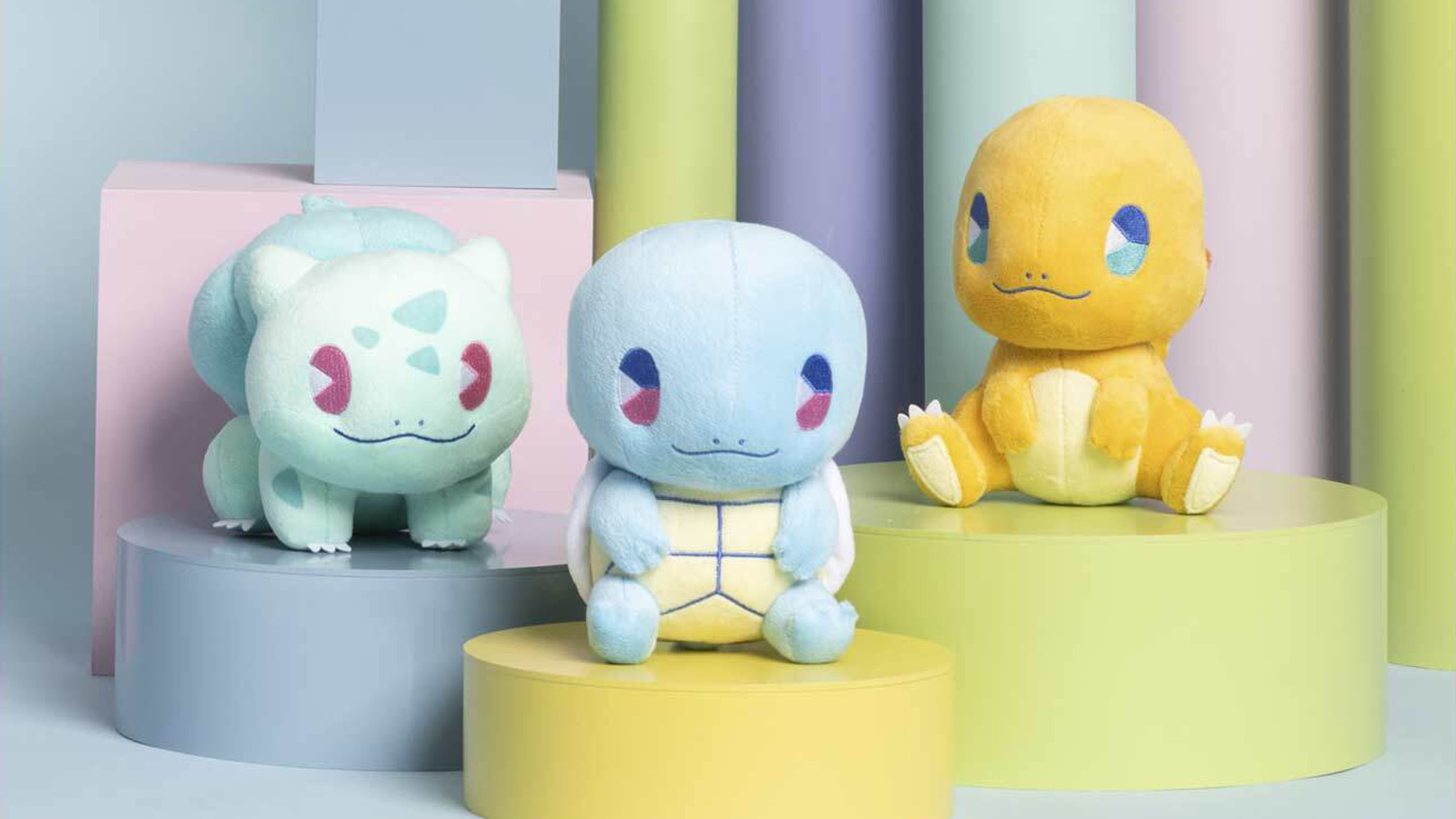 A photo of the three starter Pokemon in the Pokémon Soda Pop Plush&nbsp;collection. There is a Bulbasaur, Squirtle, and Charmander and each one has big eyes and a cutesy pastel look.
