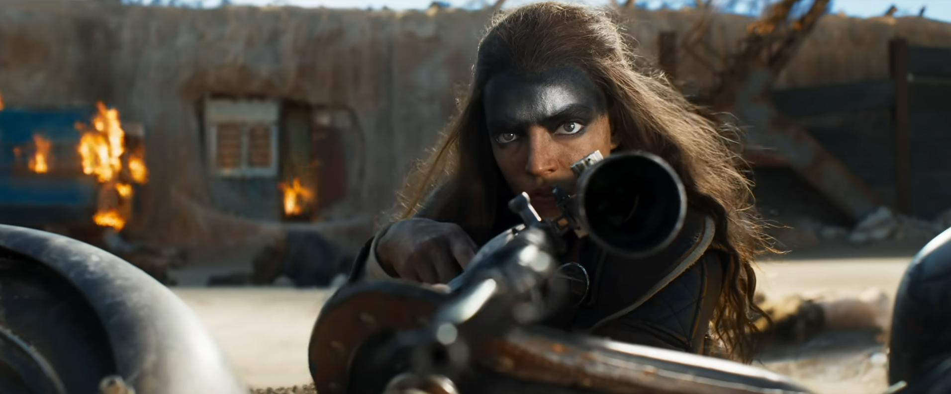 Anya Taylor-Joy as a Furiosa in Furiosa holding a sniper rifle with grease painted on her forehead 