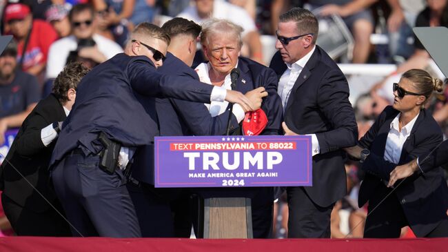 Кандидата в президенты США от Республиканской партии Дональда Трампа прикрывают агенты Секретной службы США на предвыборном митинге