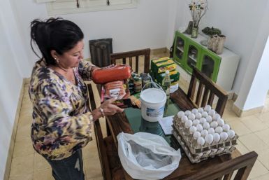 Maria Paez unpacks a box of food items sent from her children in Miami to Havana