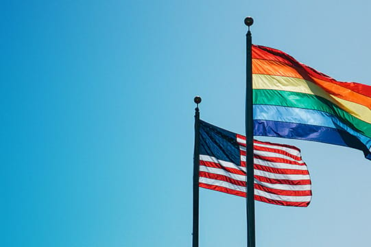 LGBTQ+ flag and United States of America flag fluttering in the wind as a symbol of pride and inclusivity
