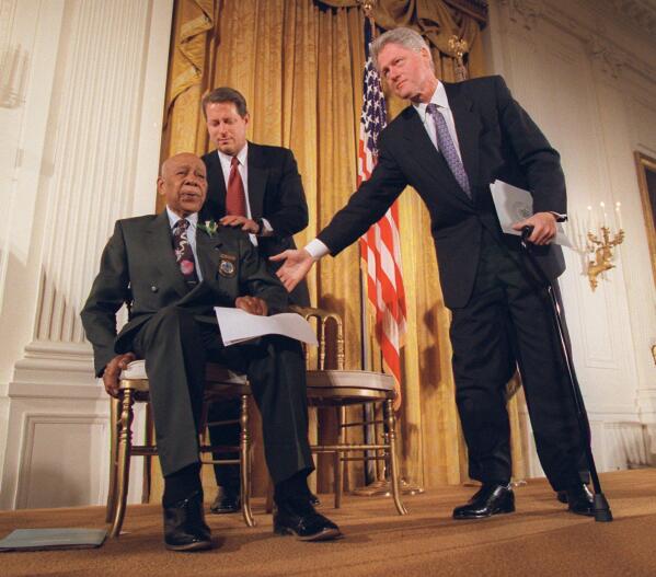 FILE - President Clinton and Vice President Al Gore, back, help Herman Shaw, 94, a Tuskegee Syphilis Study victim, during a news conference on May 16, 1997. Fifty years after the infamous Tuskegee syphilis study was revealed to the public in 1972 and halted, Manhattan-based philanthropy organization Milbank Memorial Fund is publicly apologizing for its role in the infamous Tuskegee syphilis study. (AP Photo/Doug Mills, File)