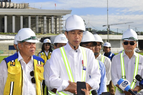 In this photo released by Indonesian Presidential Palace, Indonesian President Joko Widodo, center, talks to journalists after he inspected the presidential palace construction site at the new capital city Nusantara in Penajam Paser Utara, East Kalimantan, Indonesia, Wednesday, June 5, 2024.(Vico/Indonesian President Palace via AP)