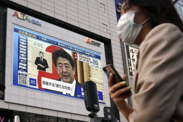 A public screen shows Japanese Prime Minister Shinzo Abe speaking at a press conference Monday, May 25, 2020, in Tokyo. Abe lifted a coronavirus state of emergency in Tokyo and four other remaining areas on Monday, ending the restrictions nationwide as businesses begin to reopen. (AP Photo/Eugene Hoshiko)