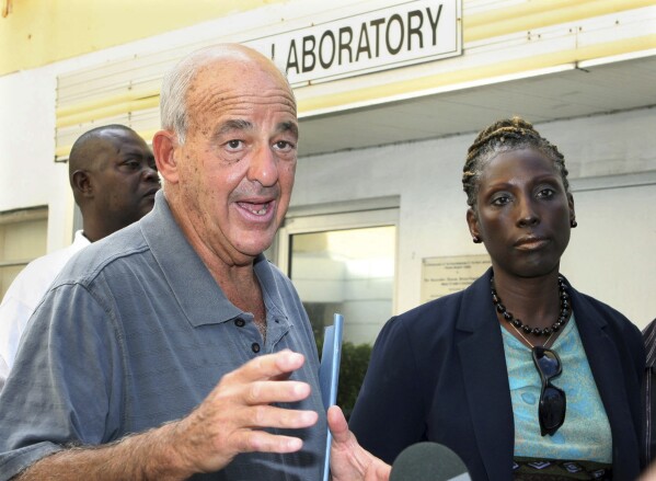 FILE - Pathologist Dr. Cyril Wecht, center, talks to the media while Bahamas' head coroner Linda Virgil, right, and attorney Michael Scott, left, listen outside the Rand Laboratory morgue at the Princess Margaret Hospital in Nassau, Bahamas, Sept. 17, 2006. Wecht, a pathologist and attorney whose biting cynicism and controversial positions on high-profile deaths such as President John F. Kennedy’s 1963 assassination caught the attention of prosecutors and TV viewers alike, died Monday, May 13, 2024. He was 93. (AP Photo/Tim Aylen, File)