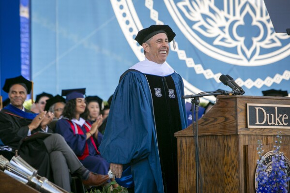 CORRECTS PHOTOGRAPHER'S NAME TO JARED LAZARUS FROM BILL SNEAD - In this photo provided by Duke University, commencement speaker Jerry Seinfeld laughs on stage during the school's graduation ceremony, Sunday, May 12, 2024, in Durham, N.C. A tiny contingent of Duke graduates opposed the pro-Israel comedian speaking at their commencement Sunday, with about 30 of the 7,000 students leaving their seats and chanting “Free Palestine!” amid a mix of boos and cheers. (Jared Lazarus/Duke University via AP)