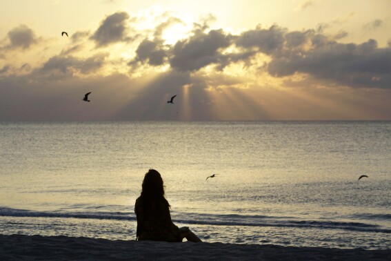 FILE - A woman meditates on the beach in Miami Beach, Fla., on April 28, 2010. Research shows a daily meditation practice can reduce anxiety, improve overall health and increase social connections, among other benefits. (AP Photo/Lynne Sladky, File)