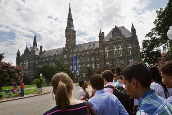 FILE - In this July 10, 2013, file photo, prospective students tour Georgetown University's campus in Washington. Georgetown University will give preference in admissions to the descendants of slaves owned by the Maryland Jesuits as part of its effort to atone for profiting from the sale of enslaved people, the president of the prominent Jesuit university in Washington announced Thursday, Sept. 1, 2016. (AP Photo/Jacquelyn Martin, File)