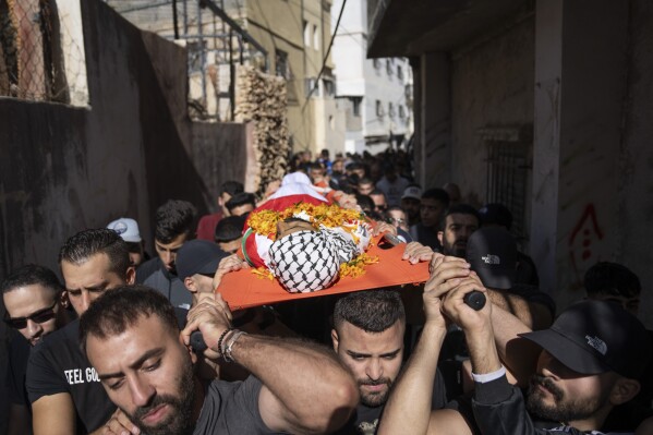 Palestinians carry the body of Ibrahim Zayed, 29, during his funeral in the West Bank refugee camp of Qalandia, south of Ramallah, Friday, Nov. 3, 2023. Zayed was killed during an Israeli army raid in Qalandia early morning, Palestinian Health Ministry said. (AP Photo/Nasser Nasser)