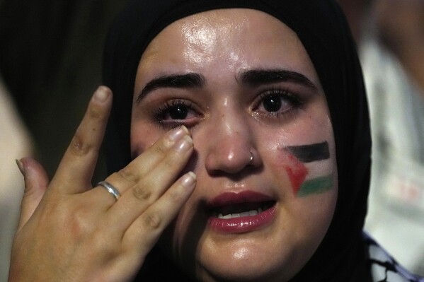 A woman with a Palestinian flag painted on her face cries during a protest against Israeli airstrikes on Gaza in Madrid, Spain, Monday, Oct. 9, 2023. (AP Photo/Paul White, File)