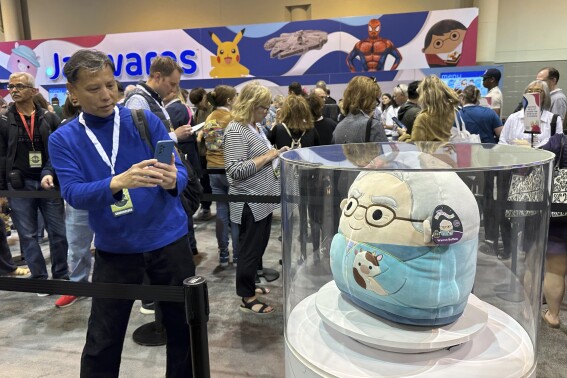 A person takes a photo of the Warren Buffett and Charlie Munger Squishmallows before Saturday's Berkshire Hathaway shareholders meeting in Omaha, Neb., on Friday, May 3, 2024. are again one of the hottest item for sale this year at the Berkshire Hathaway shareholders meeting. (AP Photo/Josh Funk)