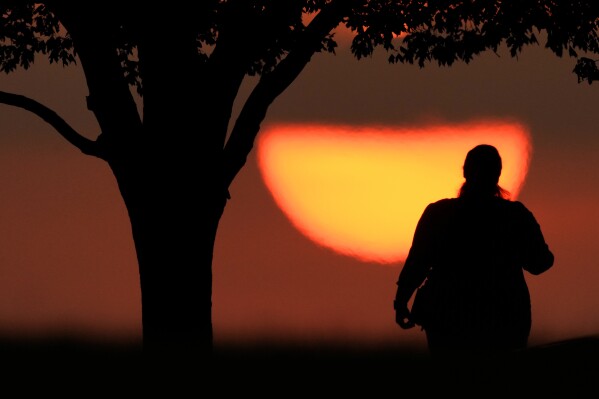 FILE - A woman watches the sun set on a hot day, Aug. 20, 2023, in Kansas City, Mo. A new study on Tuesday, May 14, 2024, finds that the broiling summer of 2023 was the hottest in the Northern Hemisphere in more than 2,000 years. (AP Photo/Charlie Riedel, File)