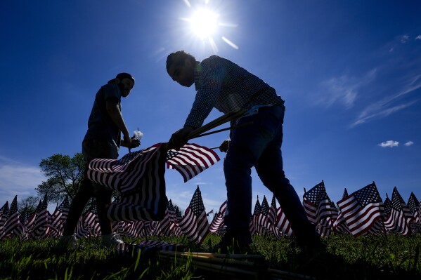 Volunteers help put up a field of flags near the War Memorial Thursday, May 23, 2024, in Milwaukee. The Memorial Day tribute will feature 27,316 American flags representing Wisconsin residents who paid the ultimate price for freedom in service to our nation. (AP Photo/Morry Gash)