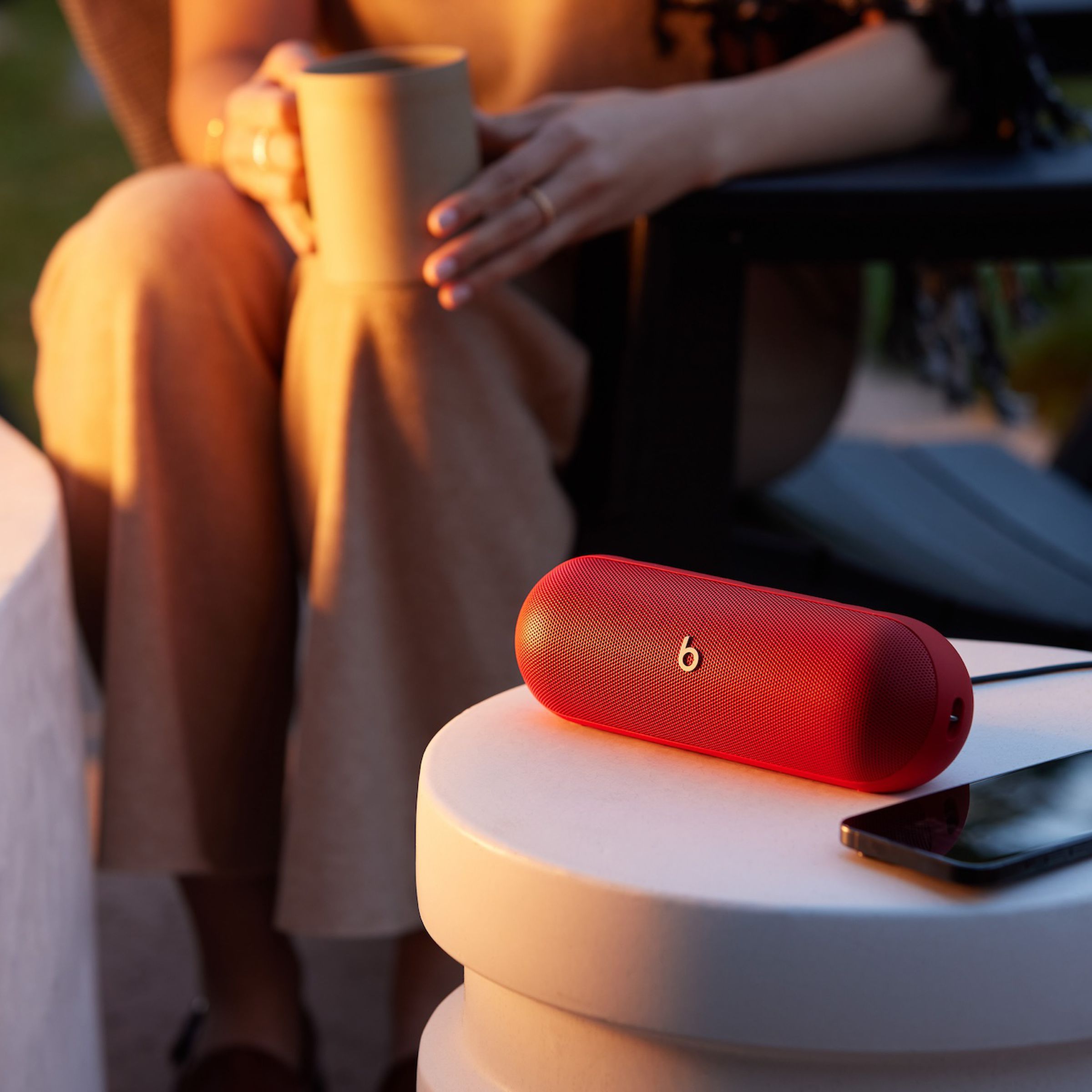 A marketing image of the Beats Pill speaker with someone holding a coffee mug in the background.