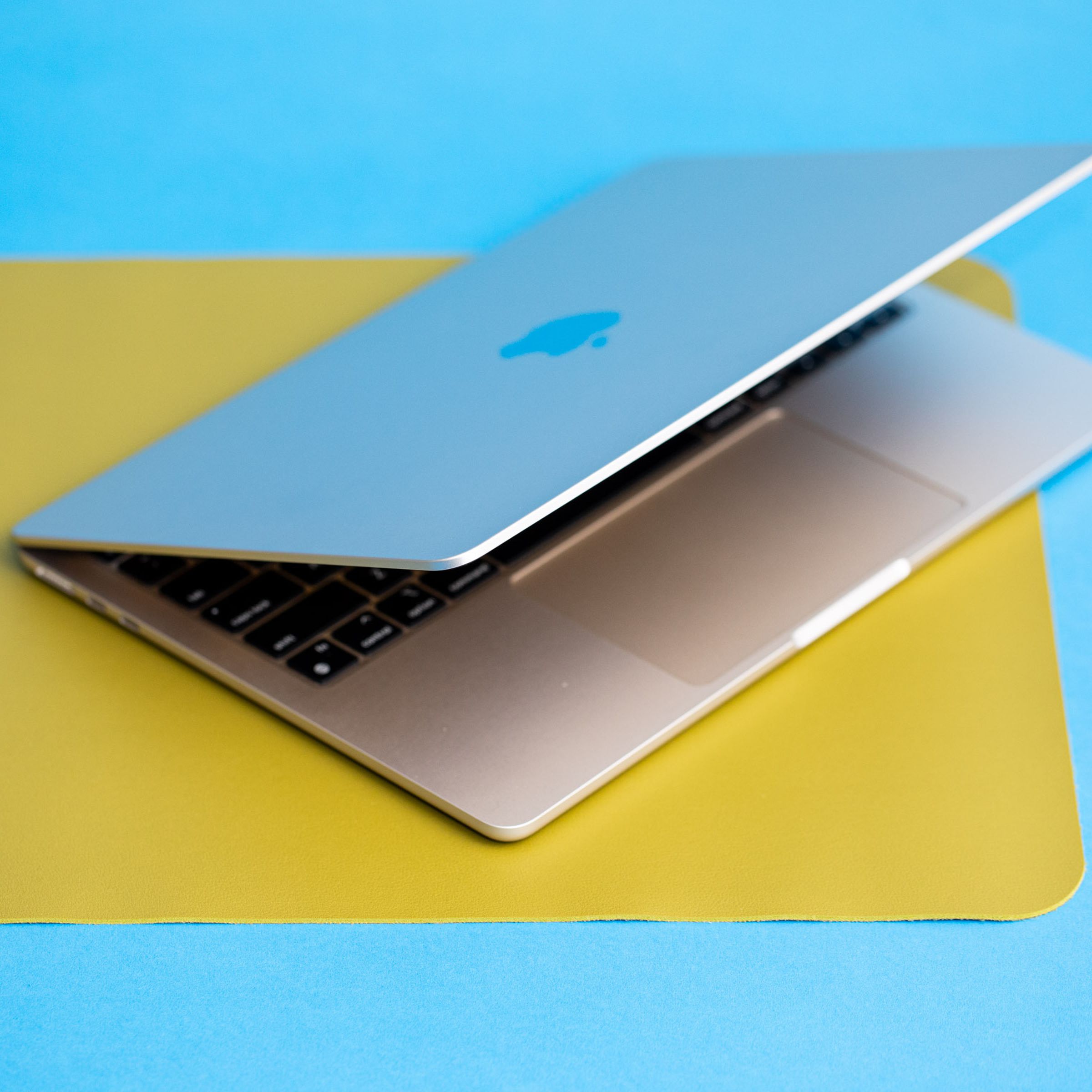 The 13-inch MacBook Air partially open sitting on a yellow mat.