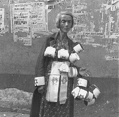 An emaciated woman sells the compulsory Star of David armbands for Jews. In the background are concert posters; almost all are destroyed. Warsaw ghetto, Poland, September 19, 1941.
This photograph was taken by Heinrich Joest, a German army sergeant during World War II. On September 19, 1941, he took 140 images of every aspect of life and death in the Warsaw ghetto. 