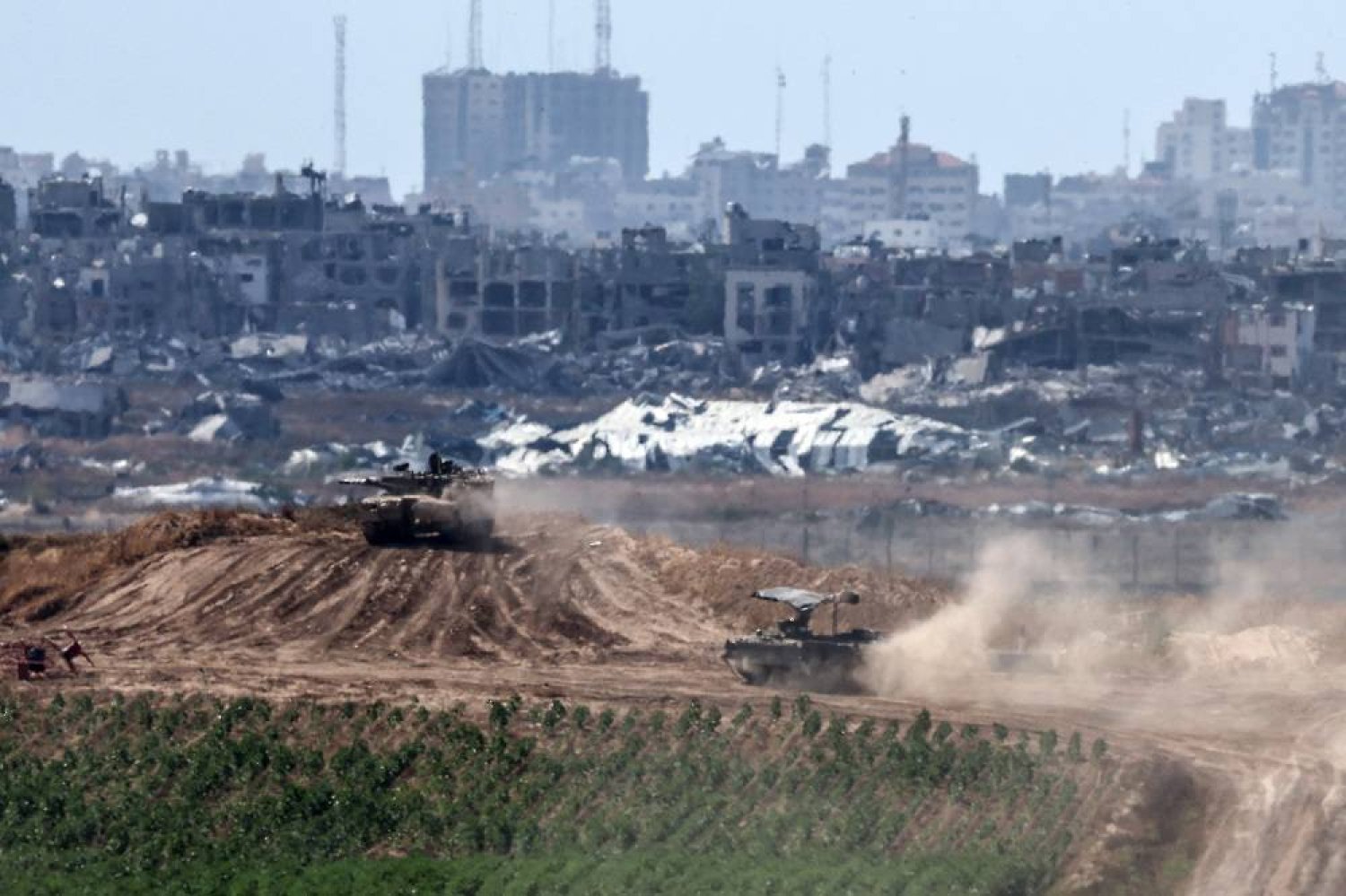 Israeli tanks maneuver along the border with the Gaza Strip, near the Palestinian city of Jabalia (background), as seen from the Israeli side of the border, southern Israel, 13 May 2024. (EPA)