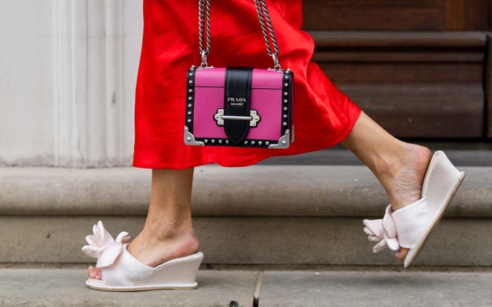 woman wearing a red slip skirt, pink purse, and while floral mule sandals