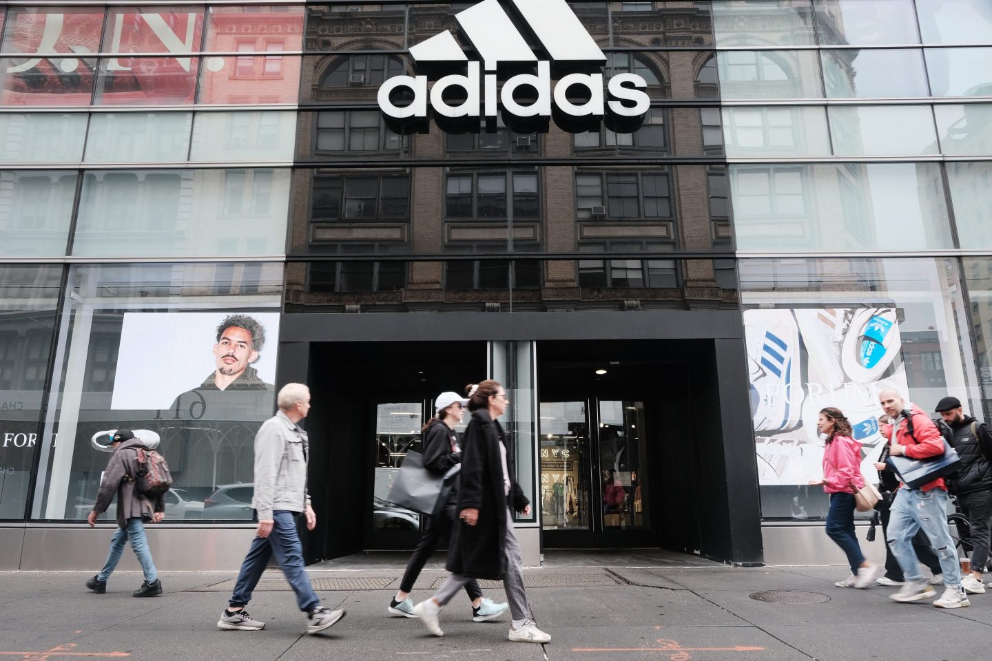 People walk outside of an Adidas store.