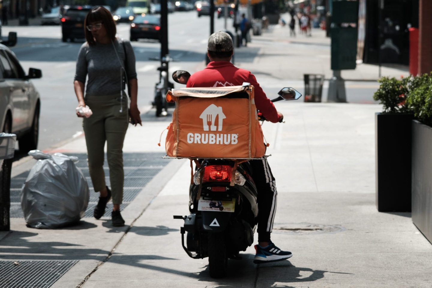 An app-based delivery worker waits outside of a restaurant in New York City.