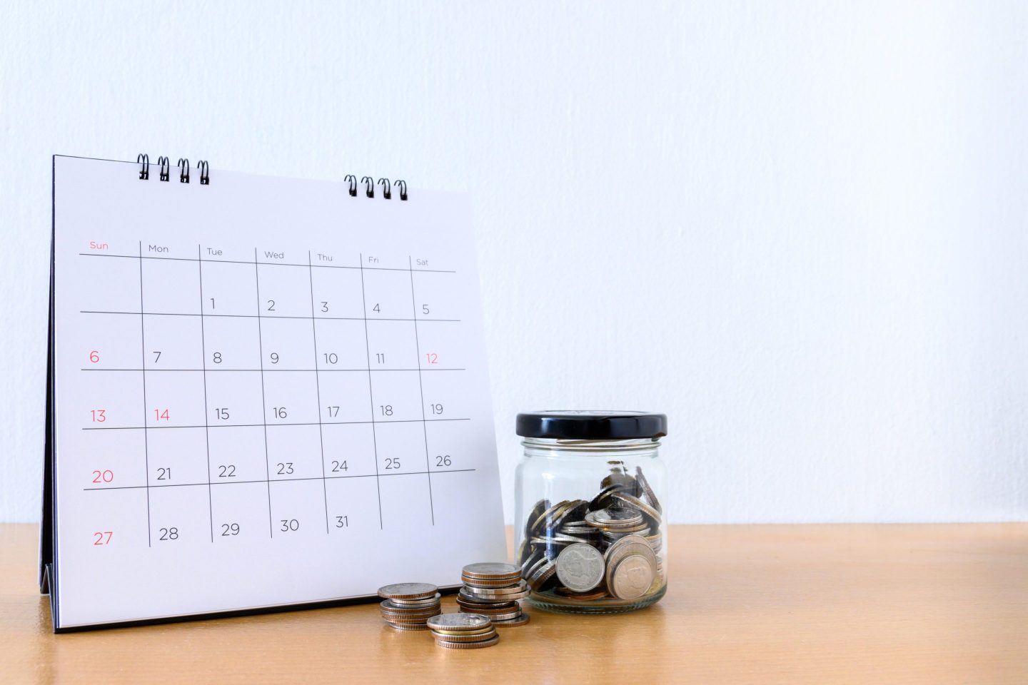 Calendar With Days and coin in the jar on wood table