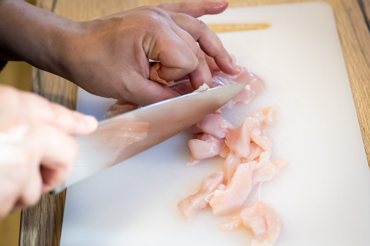 CARDIFF, WALES &#8211; NOVEMBER 6: In this photo illustration, A woman cuts raw chicken with a knife on a chopping board November 6, 2023 in Cardiff, Wales. (Photo by Matthew Horwood/Getty Images)