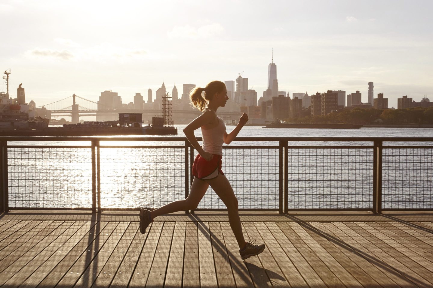 Side view of woman jogging on pier, Manhattan, New York, USA