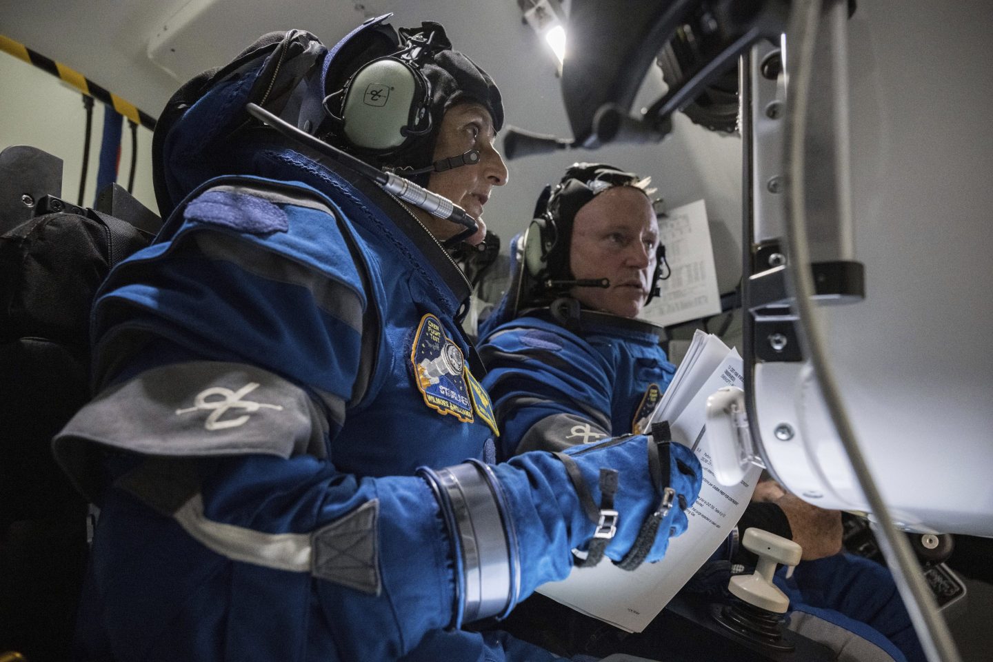 astronauts sit in space capsule simulator