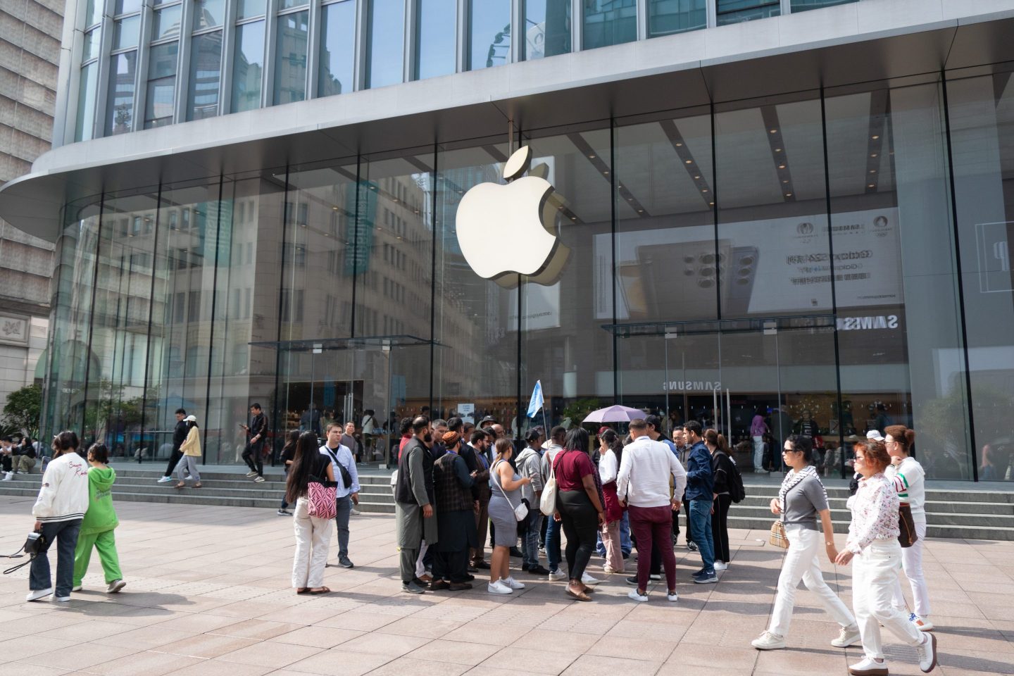 Foreign tourists walk past an Apple store in Shanghai, on April 11, 2024.