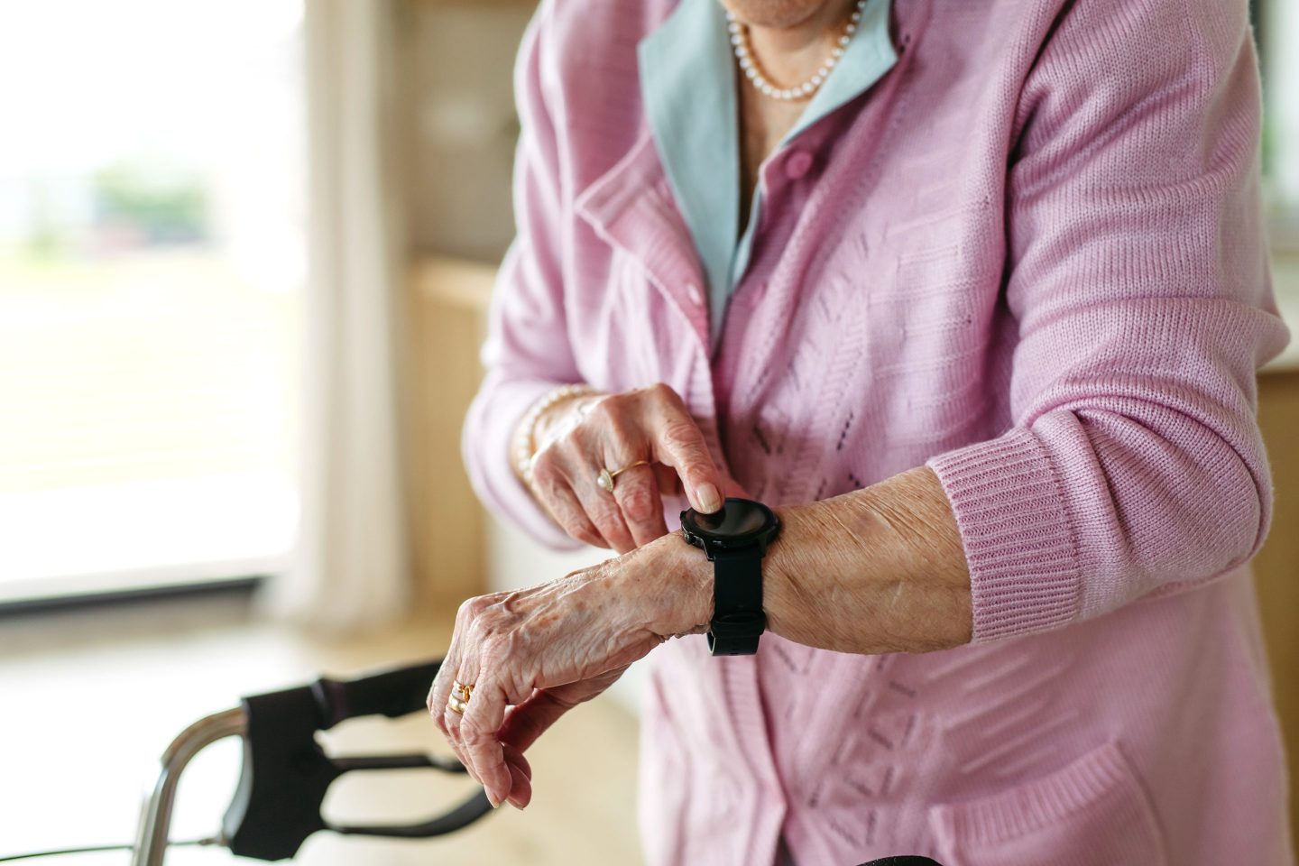 Close up of Elderly woman looking at medical alert watches on her wrist. Personal emergency response systems watches, designed for seniors to call for help in emergencies.