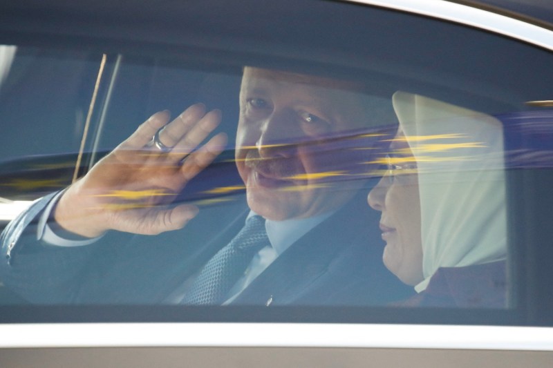 Turkish President Recep Tayyip Erdogan waves as he sits inside a car with his wife Emine Erdogan as a European flag is reflected on the car window after disembarking at Berlin's Tegel airport for his three-day official visit to Germany, on September 27, 2018.