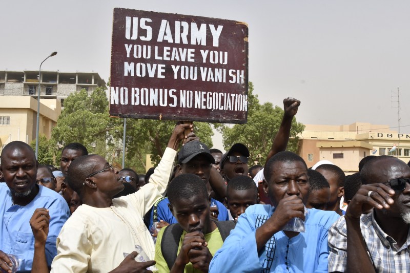 Protesters react as a man holds up a sign demanding that U.S. soldiers leave Niger without negotiation during a demonstration in Niamey. The sign reads: "U.S. Army: You leave, you move, you vanish. No bonus, no negotiation."