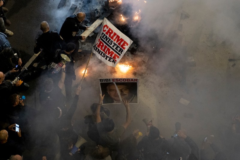 Police officers extinguish a fire during a protest against the Israeli Prime  Minister Benjamin Netanyahu and his government on March 16, in Tel Aviv, Israel.