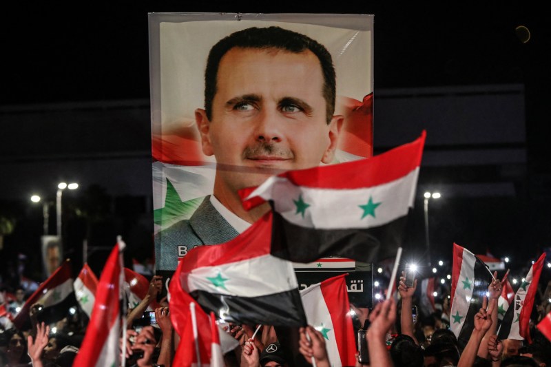 Syrians wave national flags and carry a large portrait of their president as they celebrate in the streets of the capital Damascus, a day after an election set to give the current President Bashar al-Assad a fourth term, on May 27, 2021.