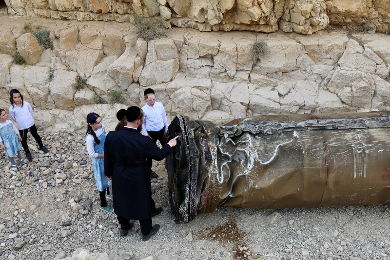 A man shows children the debris of an intercepted Iranian missile near Arad, Israel, on April 28.