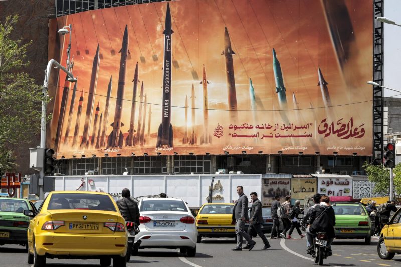 Cars pass a billboard depicting Iranian ballistic missiles on Valiasr Square in central Tehran on April 15.