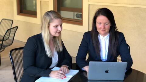 Master's students Mariann Varga and Elani Owen work together at a laptop.