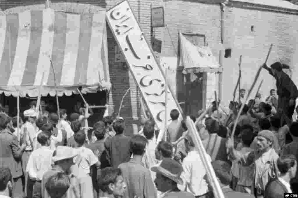 A crowd of demonstrators tears down the sign of the Iran Party, part of Mossadegh&#39;s National Front, at its headquarters on August 19. 