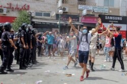 Protesters face police officers during a demonstration in Tunis, Tunisia, July 25, 2021. Rallies broke out Sunday in several Tunisian cities as protesters expressed anger at the deterioration of the country's health, economic and social situatiion.