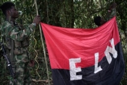 FILE - Rebels of the National Liberation Army hold a banner in the northwestern jungles in Colombia, Aug. 30, 2017.