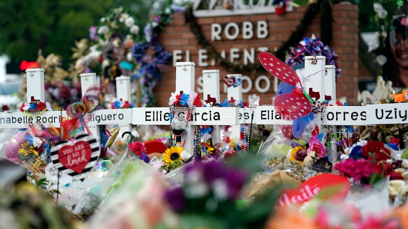 FILE - Crosses are surrounded by flowers and other items at a memorial, Thursday, June 9,...